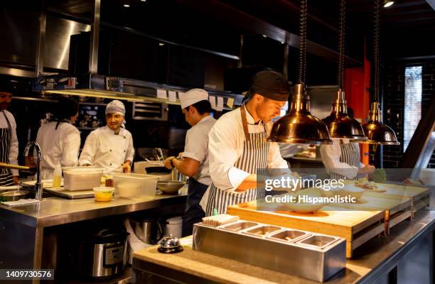 chef decorating a plate while working at a commercial kitchen - cozinha industrial imagens e fotografias de stock