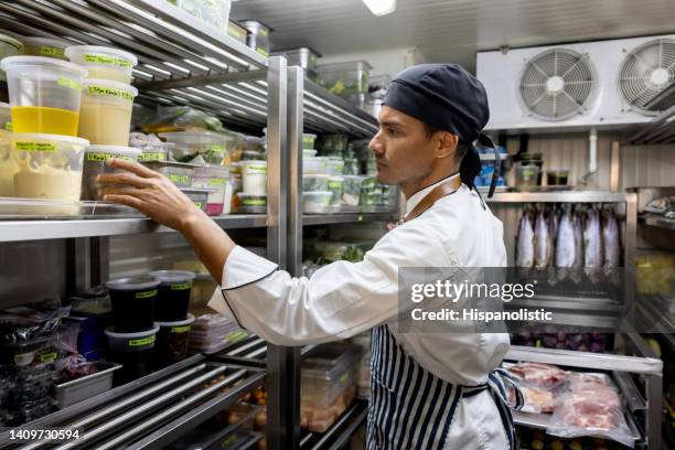 chef working at a restaurant and looking for some ingredients in the pantry - voorraadkast stockfoto's en -beelden
