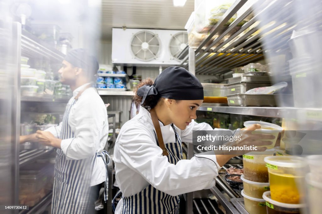 Cocineros trabajando en un restaurante y buscando ingredientes en la despensa