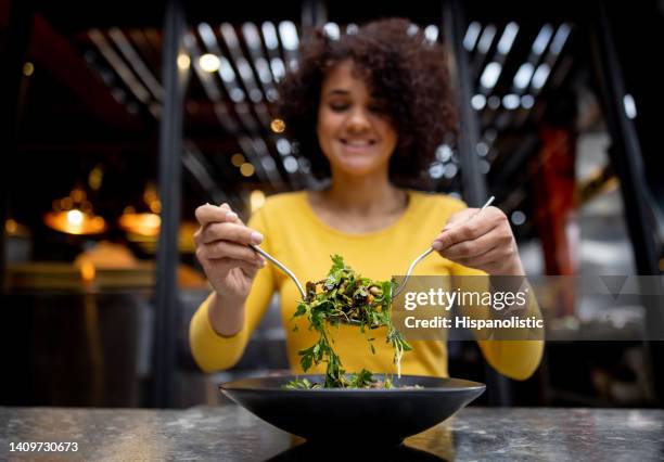 healthy woman eating a salad at a restaurant - veganism stock pictures, royalty-free photos & images