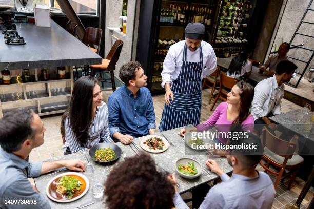 chef parlant à un groupe d’amis mangeant dans un restaurant - professional occupation photos et images de collection