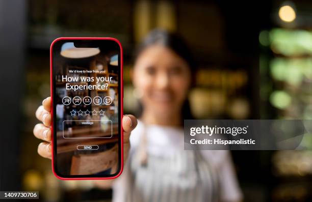 waitress displaying an app to rate your experience at a restaurant - online review stockfoto's en -beelden