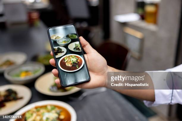 chef tomando una foto de un plato en un restaurante usando un teléfono celular - servizio fotografico fotografías e imágenes de stock