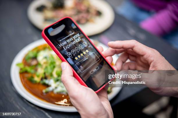 mann, der seine erfahrung in einem restaurant mit einer app auf einem mobiltelefon bewertet - bewertung stock-fotos und bilder