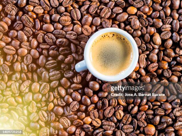 full frame of the textures formed by roasted coffee beans and a cup of coffee, arabica and robusta. - caffeine molecule stock pictures, royalty-free photos & images
