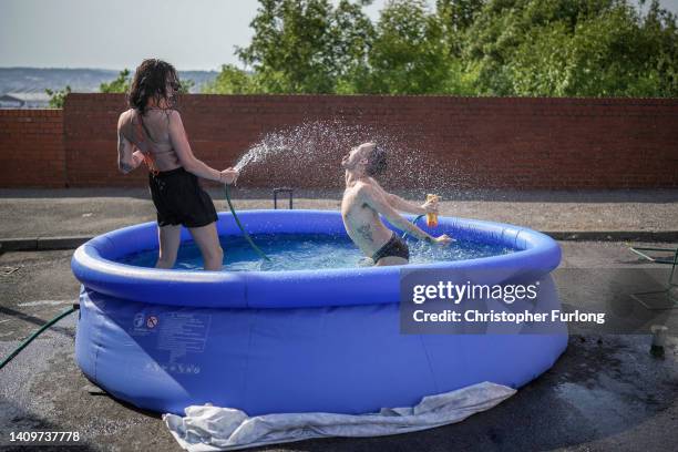 Residents take a dip in a paddling pool to cool off outside their home on July 19, 2022 in Leeds, United Kingdom. Temperatures exceeded 40C in parts...