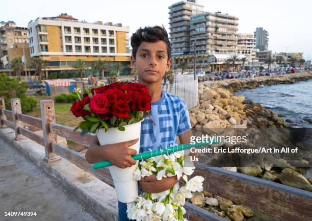 Young syrian boy selling flowers on the corniche, North Governorate, Tripoli, Lebanon on June 2, 2022 in Tripoli, Lebanon.