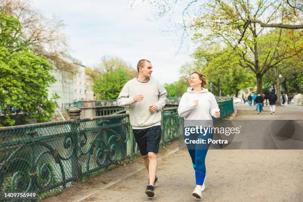 uomo e donna che fanno jogging in città - corpo normale foto e immagini stock