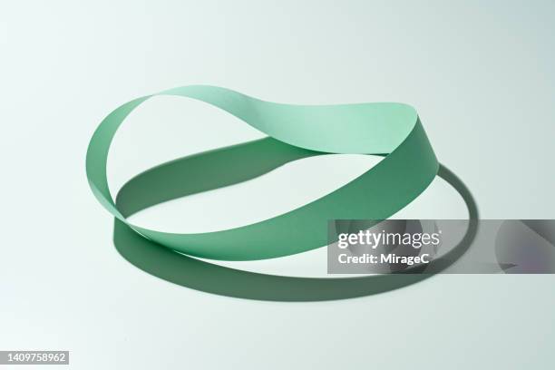 möbius or mobius strip made of green colored paper strip - lifecycle stock-fotos und bilder