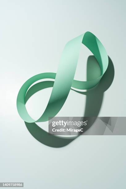 infinity mark mobius strip made of green colored paper strip - papierrolle stock-fotos und bilder