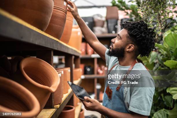 jeune vendeur travaillant sur une tablette numérique dans une jardinerie - shop seller photos et images de collection