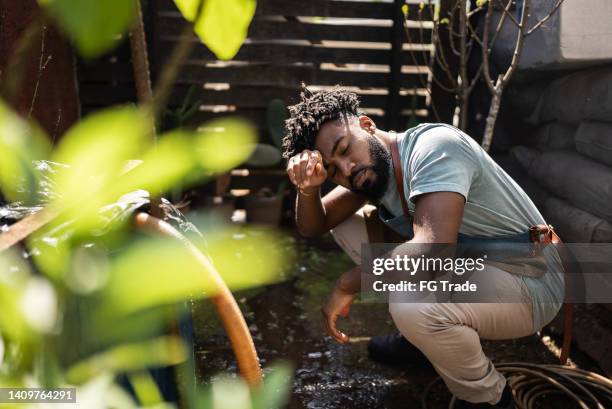 tired young man working at a garden center - agony in the garden stockfoto's en -beelden