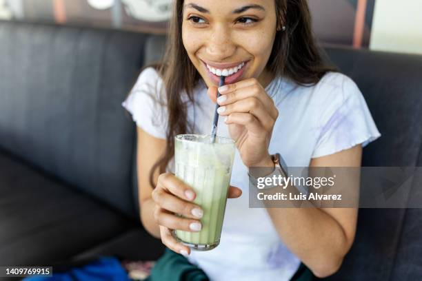 happy young woman having iced matcha latte at cafe - thé matcha photos et images de collection