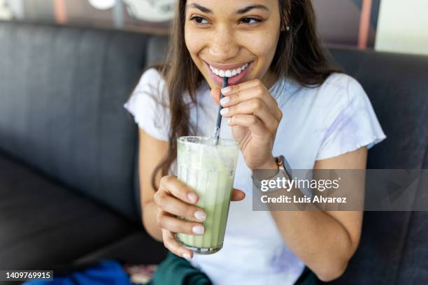 happy young woman having iced matcha latte at cafe - malt stockfoto's en -beelden