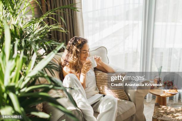 woman at home reading book and drinking coffee. - new age bildbanksfoton och bilder