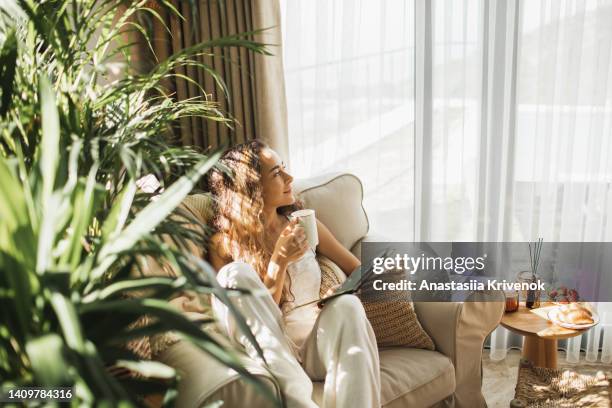 woman at home reading book and drinking coffee. - boho-stil stock-fotos und bilder