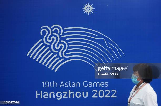 Citizen walks by a poster featuring the emblem for the 19th Asian Games Hangzhou 2022 on July 18, 2022 in Hangzhou, Zhejiang Province of China.