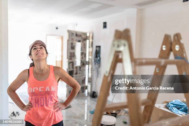 woman in her house doing renovations looks at the drywall ceiling and plans the work - drywall finishing stock pictures, royalty-free photos & images