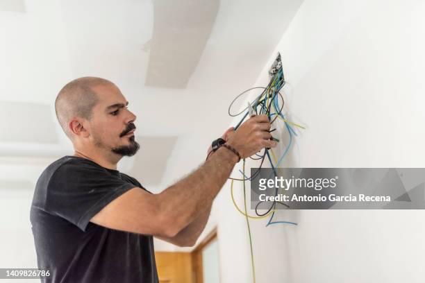 electrician places electrical circuit and cables in an electricity box - electrical fuse box stock pictures, royalty-free photos & images