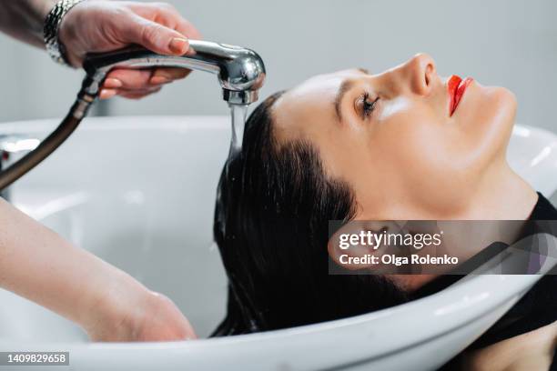 woman getting washing hair in sink in beauty salon - hairdresser washing hair stock pictures, royalty-free photos & images