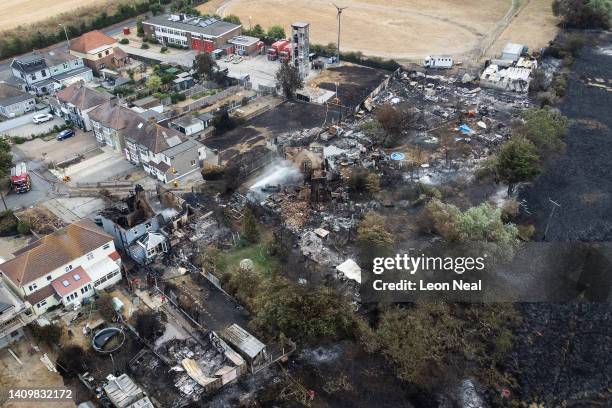 An aerial view shows the rubble and destruction in a residential area following a large blaze the previous day, on July 20, 2022 in Wennington,...