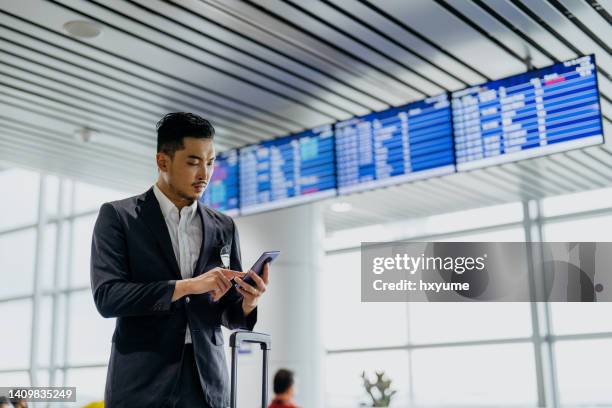 asiatischer geschäftsmann mit smartphone im flughafenterminal - kuala lumpur airport stock-fotos und bilder