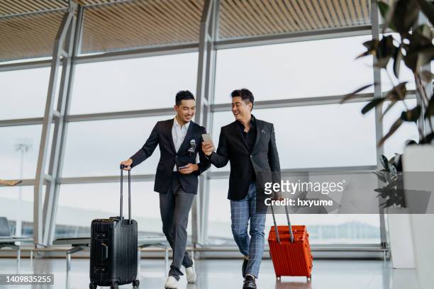 two asian businessmen going for a business trip by airplane - kuala lumpur airport stockfoto's en -beelden