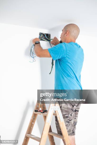 electrician places electrical circuit and cables in an electricity box - man cutting wire stockfoto's en -beelden