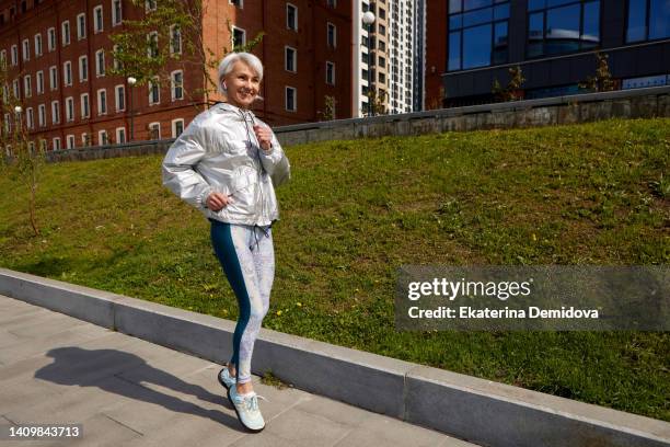 elderly woman jogging in city along promenade - senior women jogging stock pictures, royalty-free photos & images