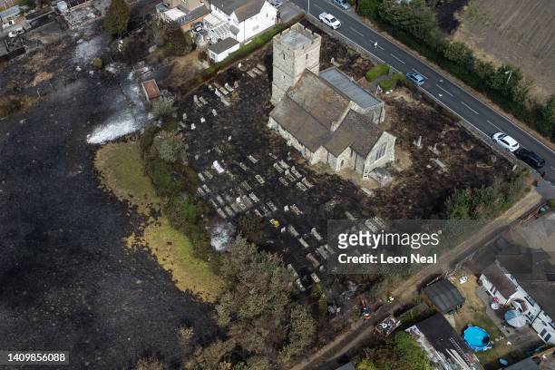 An aerial view shows the scorched graveyard around a church following a large blaze the previous day, on July 20, 2022 in Wennington, Greater London....