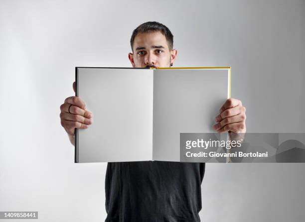 man shows the blank pages of a book - folleto papel blanco fotografías e imágenes de stock