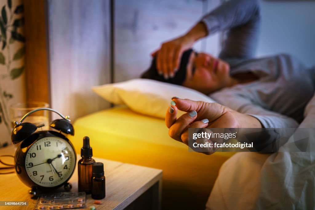 Worried woman suffering insomnia and sleep disorder taking sleeping pill