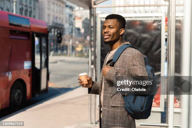 african american young man enjoying coffee while waiting for a bus - bus station stock pictures, royalty-free photos & images