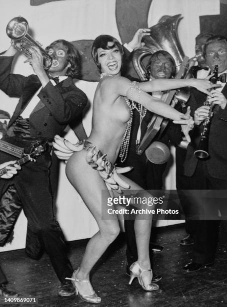 French burlesque dancer Maria Tuxedo dancing to the music of a live band, all in blackface, at a club, circa 1968. Her performance is in imitation of...