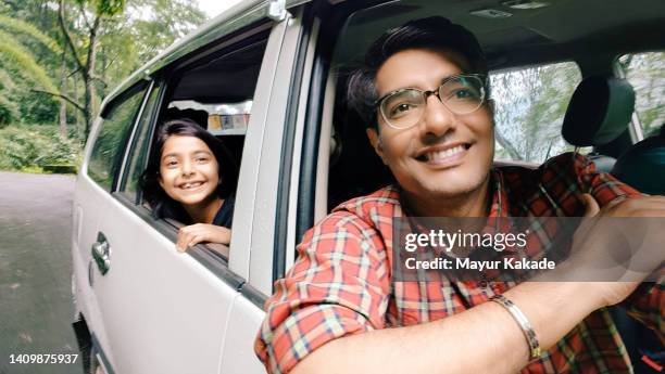 self portrait of a cheerful father and daughter looking outside window of a car - indian family vacation stock pictures, royalty-free photos & images