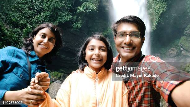 self portrait of a family in front of a waterfall - indian family vacation stock pictures, royalty-free photos & images
