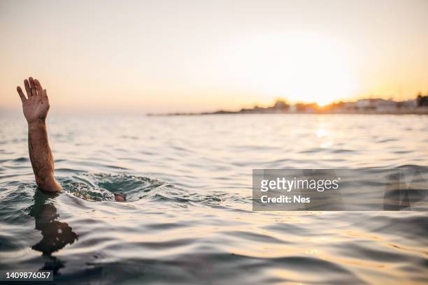un hombre se está ahogando, pidiendo ayuda con su mano - ahogarse fotografías e imágenes de stock