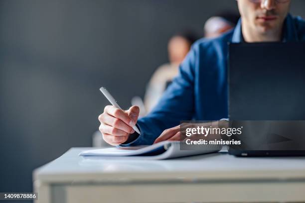 foto de cerca de manos de hombre escribiendo notas en un cuaderno durante una conferencia en la universidad - learning fotografías e imágenes de stock