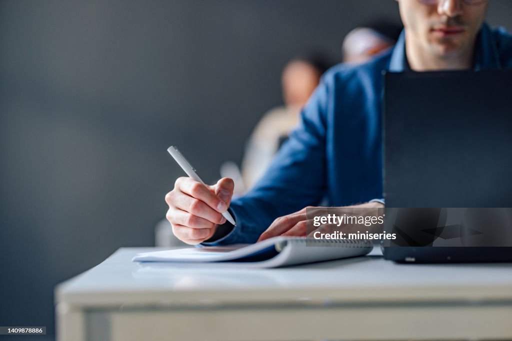 Close Up Photo Of Man Hands Writing Notes In A Notebook During Lecture At College