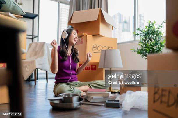 casual relax home moving break,asian young female adult wearing headphone music while searching smartphone for delivery moving agent transport during packing home stuffs things from old apartment ready to relocation moving to new home - music box 個照片及圖片檔