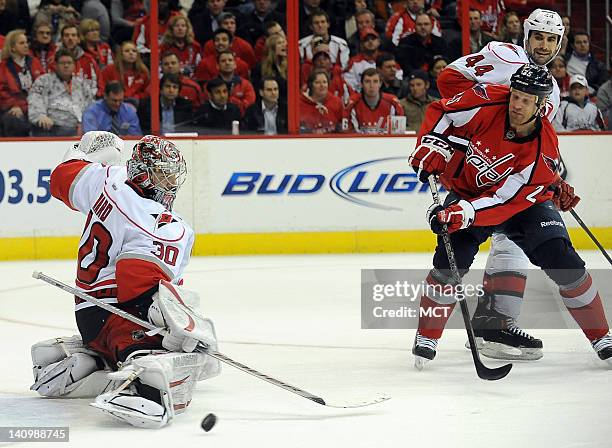 Carolina Hurricanes goalie Cam Ward turns aside a shot as Hurricanes defenseman Jay Harrison defends Washington Capitals left wing Jason Chimera in...