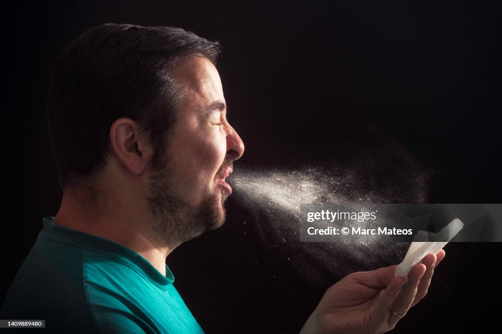 Man sneezing on dark background