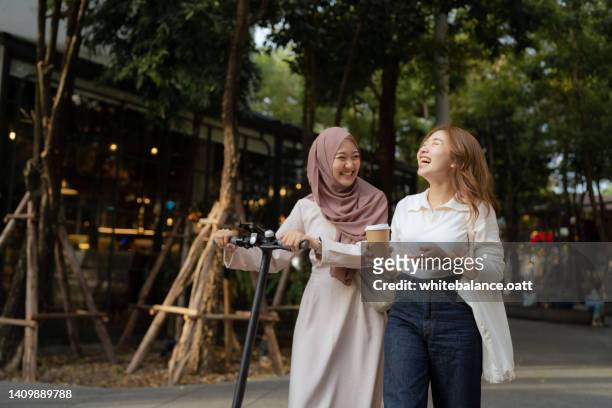 asian businesswomen chit chatting on a coffee break in public park. - coffee break outside stock pictures, royalty-free photos & images