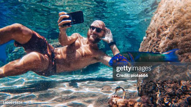 selfie con cellulare sott'acqua in mare: fotobombardamento di pesci - uomo pesci foto e immagini stock