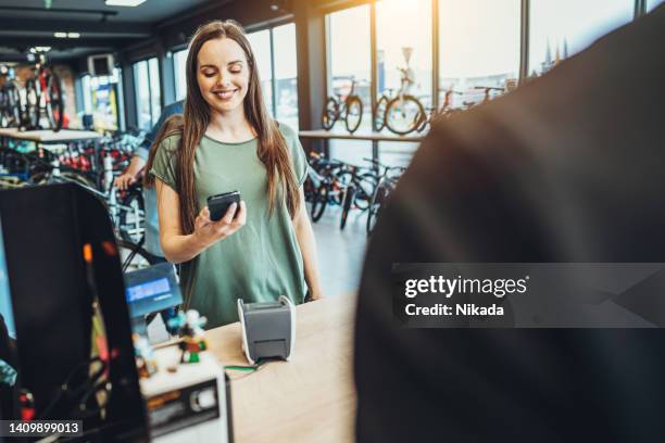 smiling woman making a payment in bicycle store - buying a bike bildbanksfoton och bilder