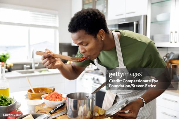 man preparing dinner in kitchen - tasting cooking stock pictures, royalty-free photos & images