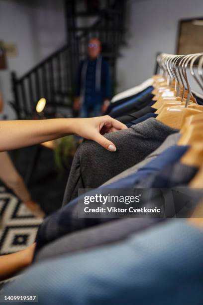 fotografía de cerca de una trabajadora tratando de encontrar el mejor traje en la tienda - barra para colgar la ropa fotografías e imágenes de stock