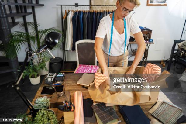 trabajadora empacando traje en una caja para el cliente en la sastrería - custom tailored suit fotografías e imágenes de stock