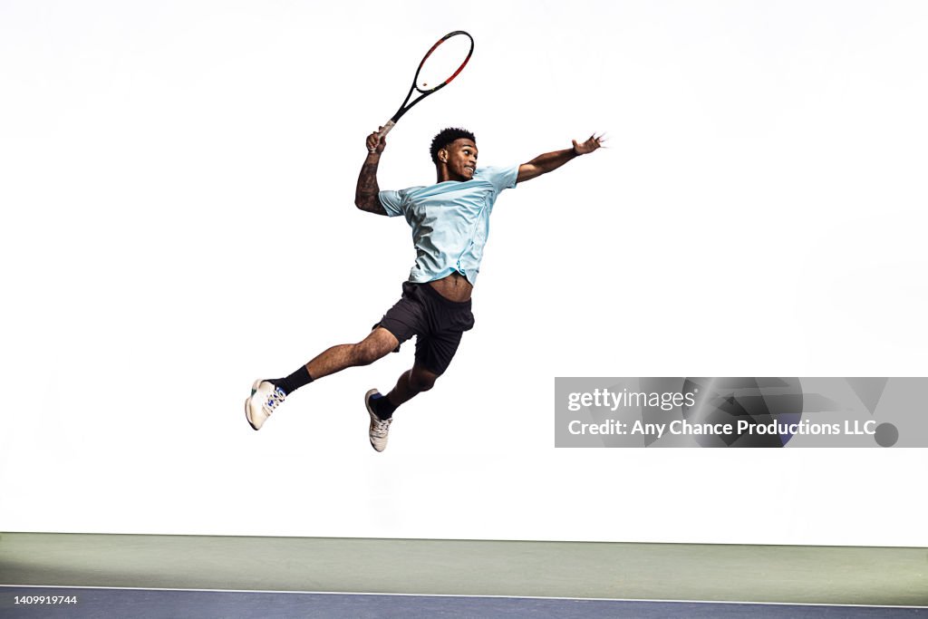 Tennis player leaps to hit a ball