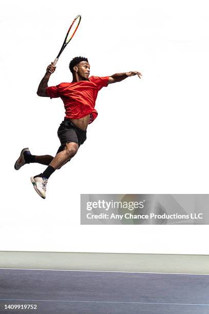 tennis player leaps forward to hit a tennis shot. - tenista fotografías e imágenes de stock